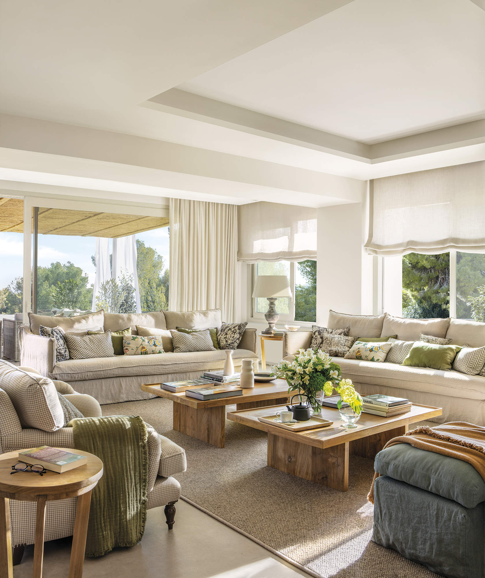 salón abierto a la terraza con sofá beige, mesas de centro de madera, alfombra y pavimento de gres, cortinas